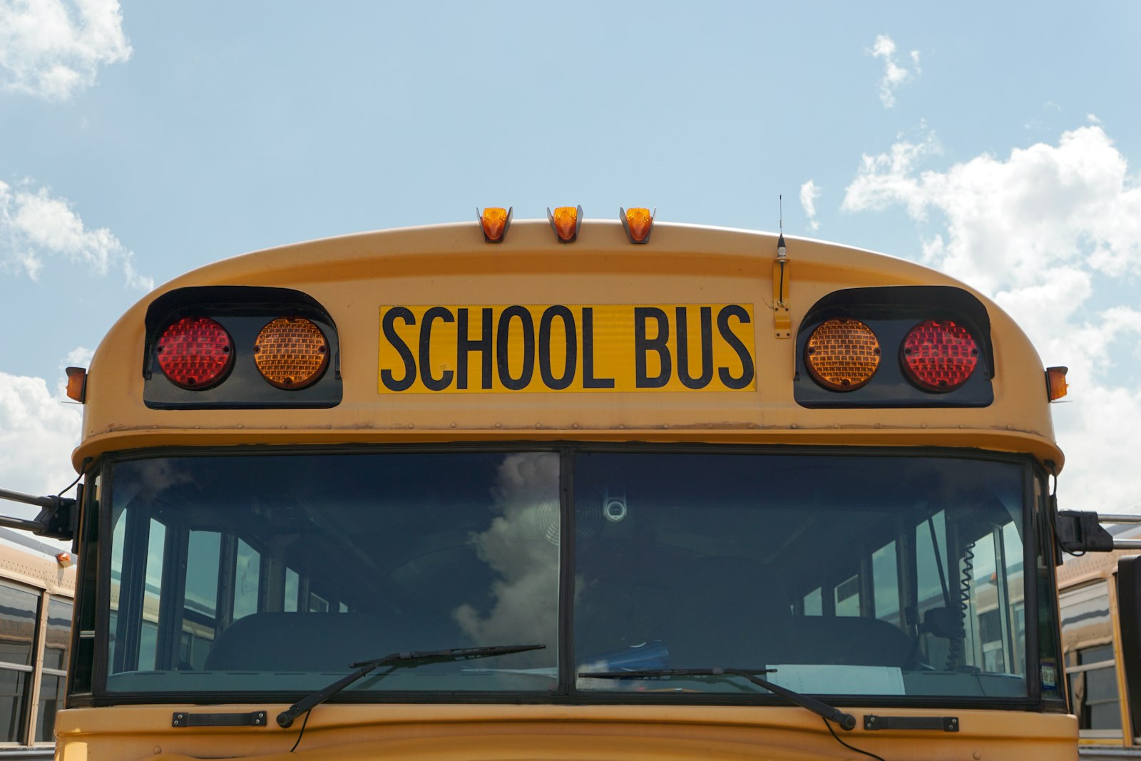 Front of a yellow school bus showing its warning lamps and SCHOOL BUS legend